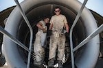 Two airmen stand in the turbine of a C-17 Globemaster 111 aircraft.