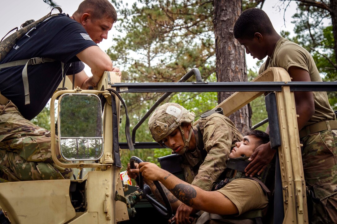 A soldier provides field medical aid to a role-playing casualty in a vehicle.