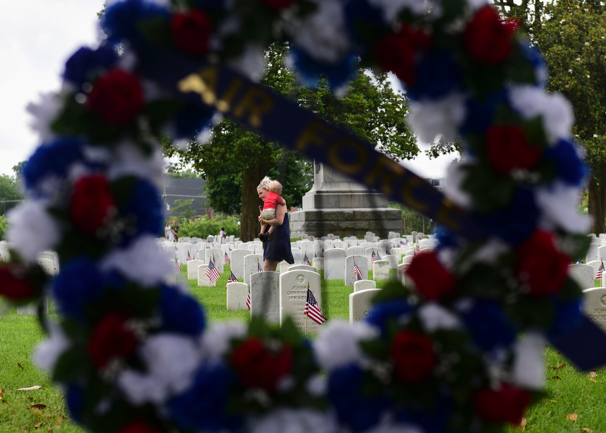 Jennifer Seeder, military spouse, carries her son, Hank, 1, while laying flowers on service members’ graves after a Memorial Day wreath-laying ceremony at Hampton National Cemetery in Hampton, Virginia, May 28, 2018. Ceremony attendees laid hundreds of flowers throughout the cemetery to honor fallen service members’ memories. (U.S. Air Force photo by Airman 1st Class Monica Roybal)