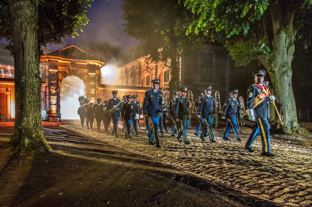 Soldiers march out from a historic building on a cobblestone-type walkway