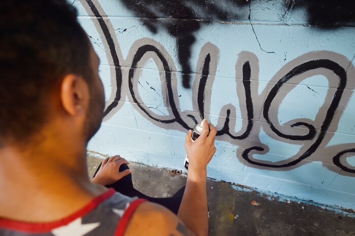 Senior Airman Jordan Guthrie, 437th Aerial Port Squadron passenger travel technician, paints a section of a 437th APS mural here May 17, 2018. Guthrie designed the art for the mural and painted the entire piece with the help of William Brown III, 437th APS packing crate supervisor. The mural highlights the “Port Dawgs” heritage. Guthrie has been drawing and practicing art since he was 10 years old.