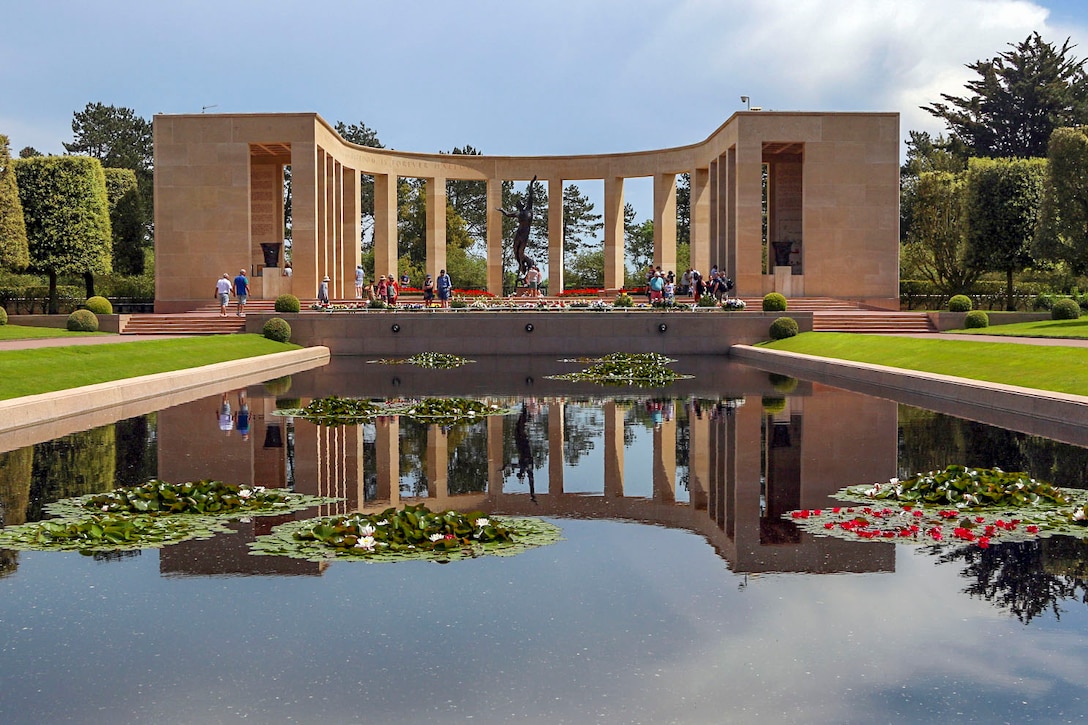 A reflecting pool shows the image of a memorial structure standing behind it.