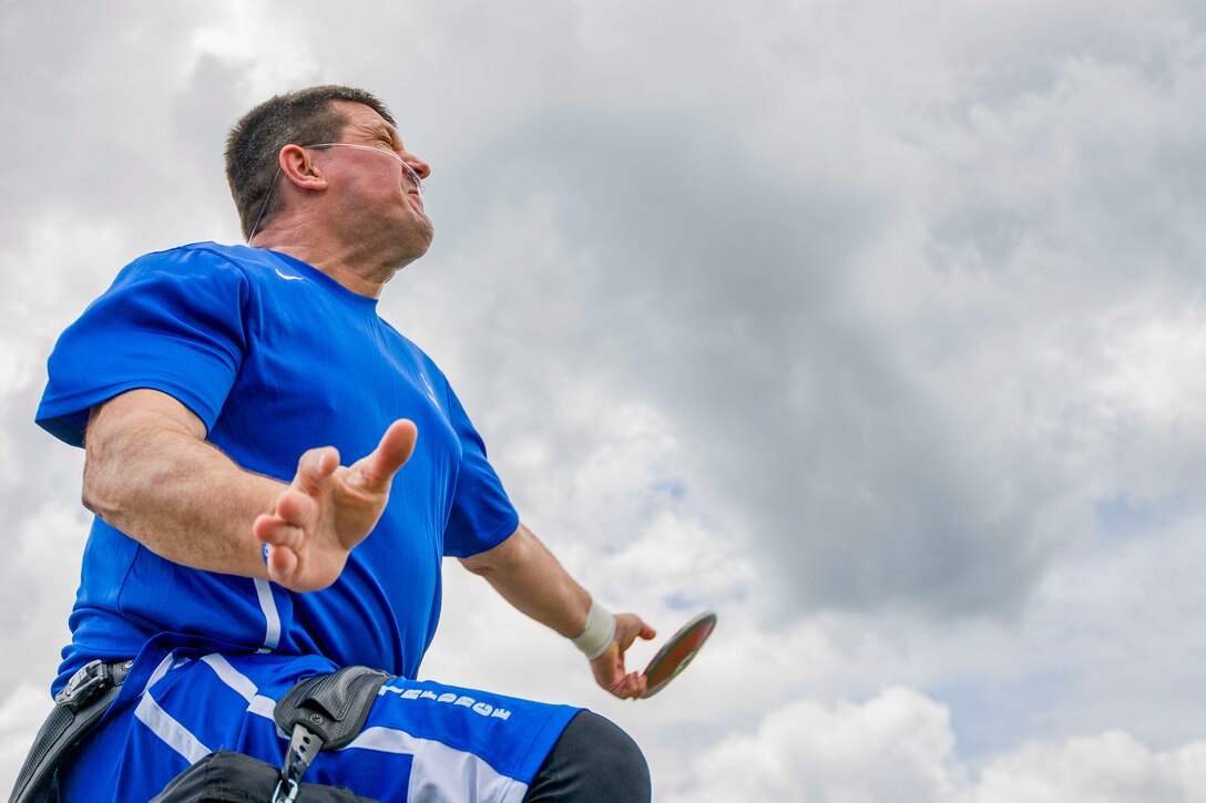 An athlete in blue team clothing prepares to throw a discus.