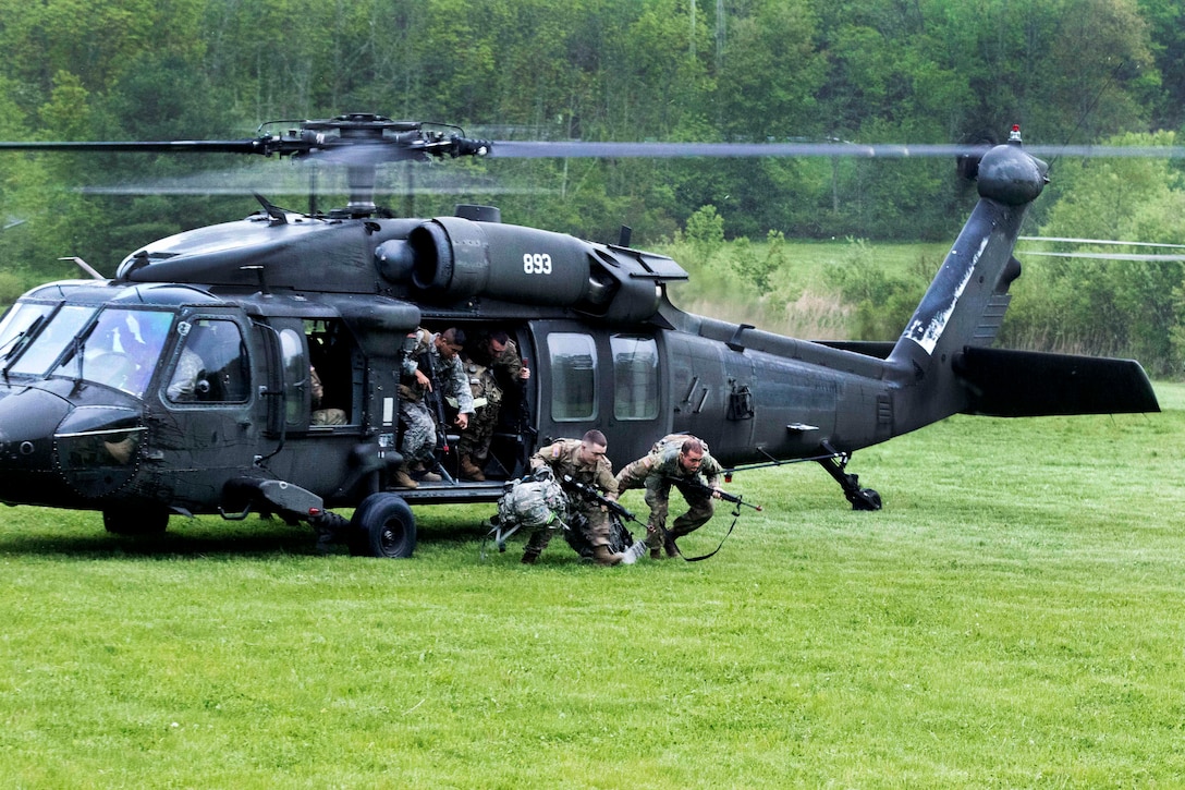 Army soldiers disembark a UH-60 Black Hawk helicopter.