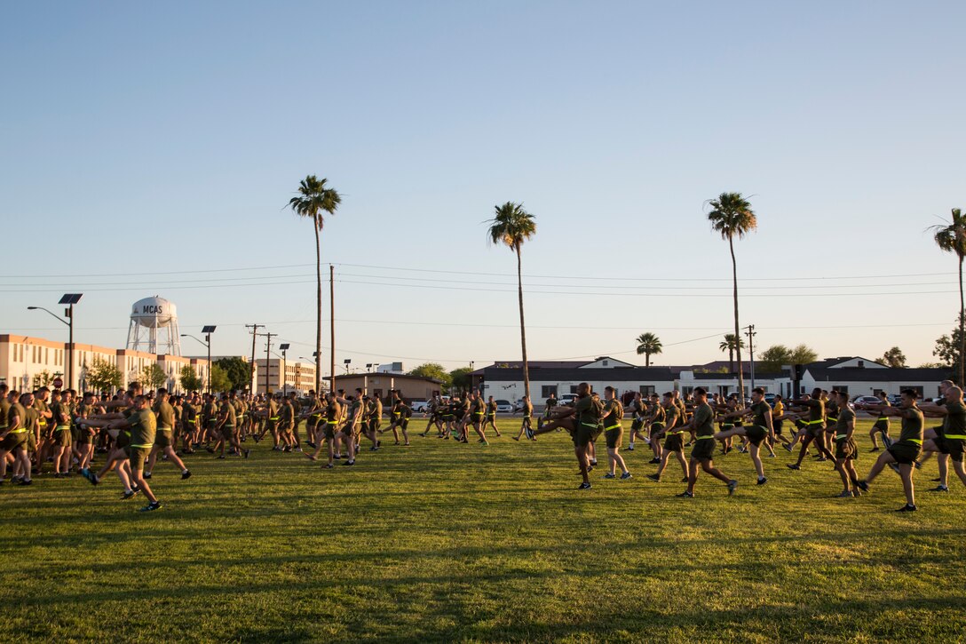 U.S. Marines stationed with Headquarters and Headquarters Squadron (H&HS), Marine Corps Air Station (MCAS) Yuma, Ariz., conduct dynamic warm up exercises prior to a motivational run on MCAS Yuma, Ariz., May 25, 2018. H&HS conducted the motivational run to kick off the Memorial Day 96 hour liberty period, and to say farewell to Lt. Col. James S. Tanis. Lt. Col. Tanis served as the commanding officer of H&HS  for the past two years. (U.S. Marine Corps photo by Sgt. Allison Lotz)