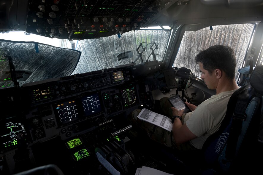 Lt. Col. Corey Akiyama, 21st Airlift Squadron C-17 Globemaster III pilot, loads a flight plan inside the cockpit before departing Anderson Air Force Base, Guam, May 16, 2018. A 21st AS C-17 aircrew, 860th Aircraft Maintenance Squadron flying crew chiefs and aeromedics with the 375th AES and 18th AES departed Anderson AFB in support of the aerial transport of patients at various military bases in the Pacific. (U.S. Air Force photo by Lan Kim)