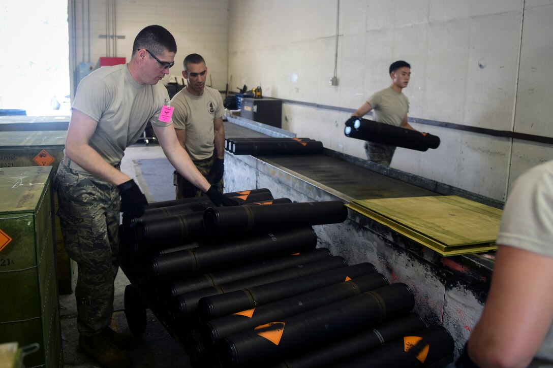 Munitions systems technicians discard 105mm round transport casings.
