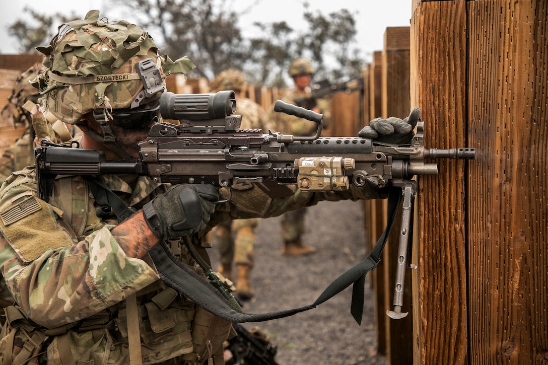 A soldier returns fire with an M249 squad automatic weapon.