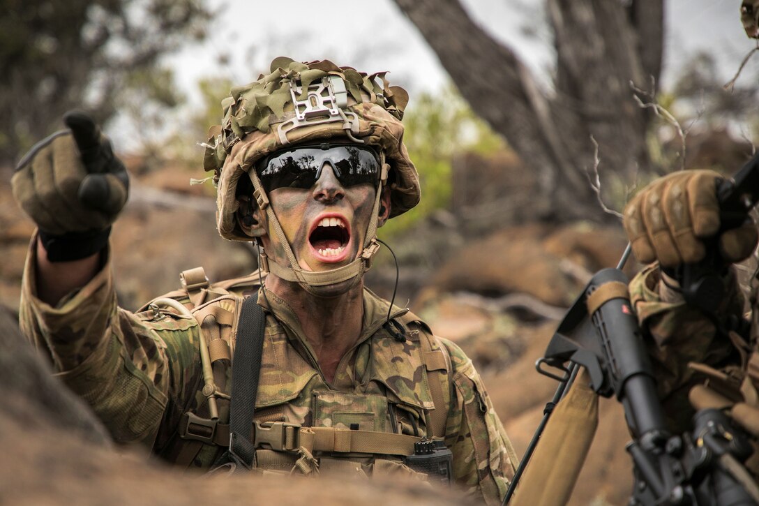 A soldier yells out orders and signals his platoon to move out.