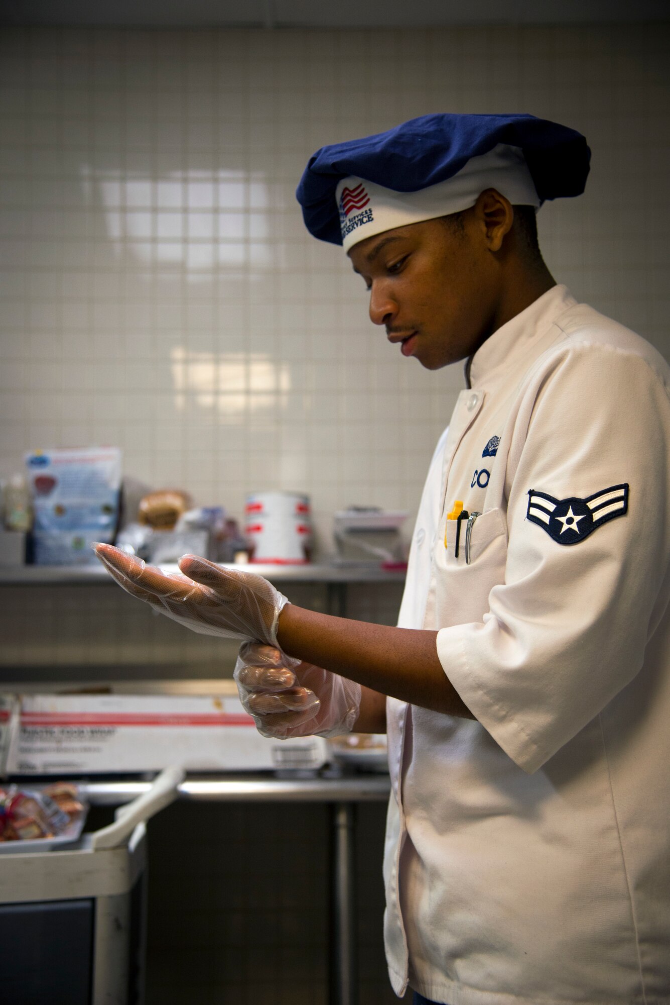 U.S. Air Force Airman 1st Class Kobe Cole, a food service journeyman assigned to the 6th Force Support Squadron, puts on sterile gloves at the Diner’s Reef dining facility on MacDill Air Force Base, Fla., May 30, 2018.