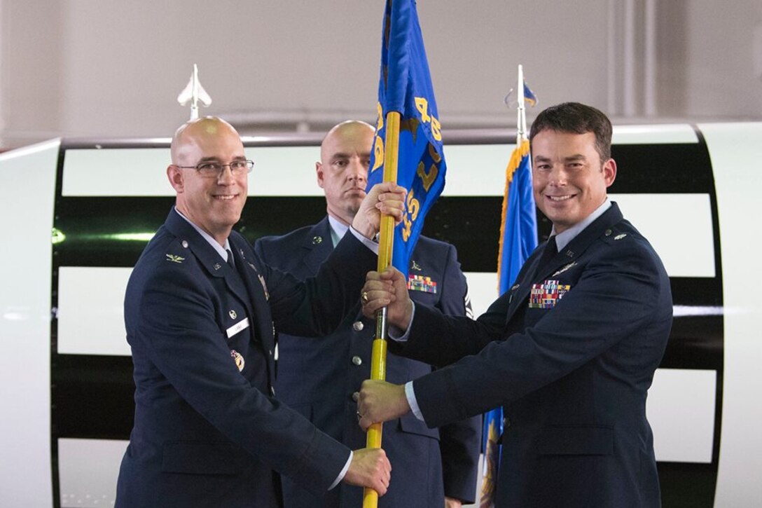 Col. Steven Lang, commander of the 45th Launch Group presents Lt. Col. Waylon Mitchell, commander of the 45th Launch Support Squadron and the 5th Space Launch Squadron, with the 45th LCSS guidon May 31, 2018 at Cape Canaveral Air Force Station, Fla. Mitchell assumed command from Lt. Col. Kathryn Cantu, and took on the role of dual-hatted commander. (U.S. Air Force photo by Airman 1st Class Zoe Thacker)
