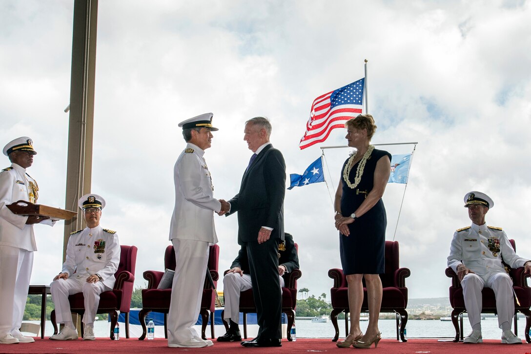 Defense Secretary James N. Mattis shakes hands with Navy Adm. Harry B. Harris Jr. on stage.