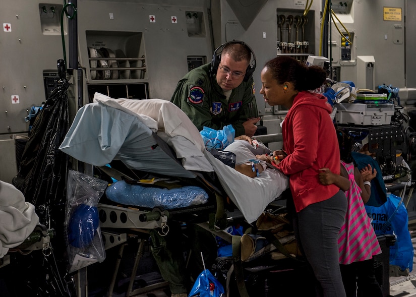 U.S. Air Force Capt. Thomas Hagan, a 123rd Medical Group critical care air transport team nurse, looks on as a patient is consoled by their family inside a C-17 Globemaster III flying over the Pacific Ocean from Travis Air Force Base, California, May 18, 2018. (U.S. Air Force photo by Lan Kim)