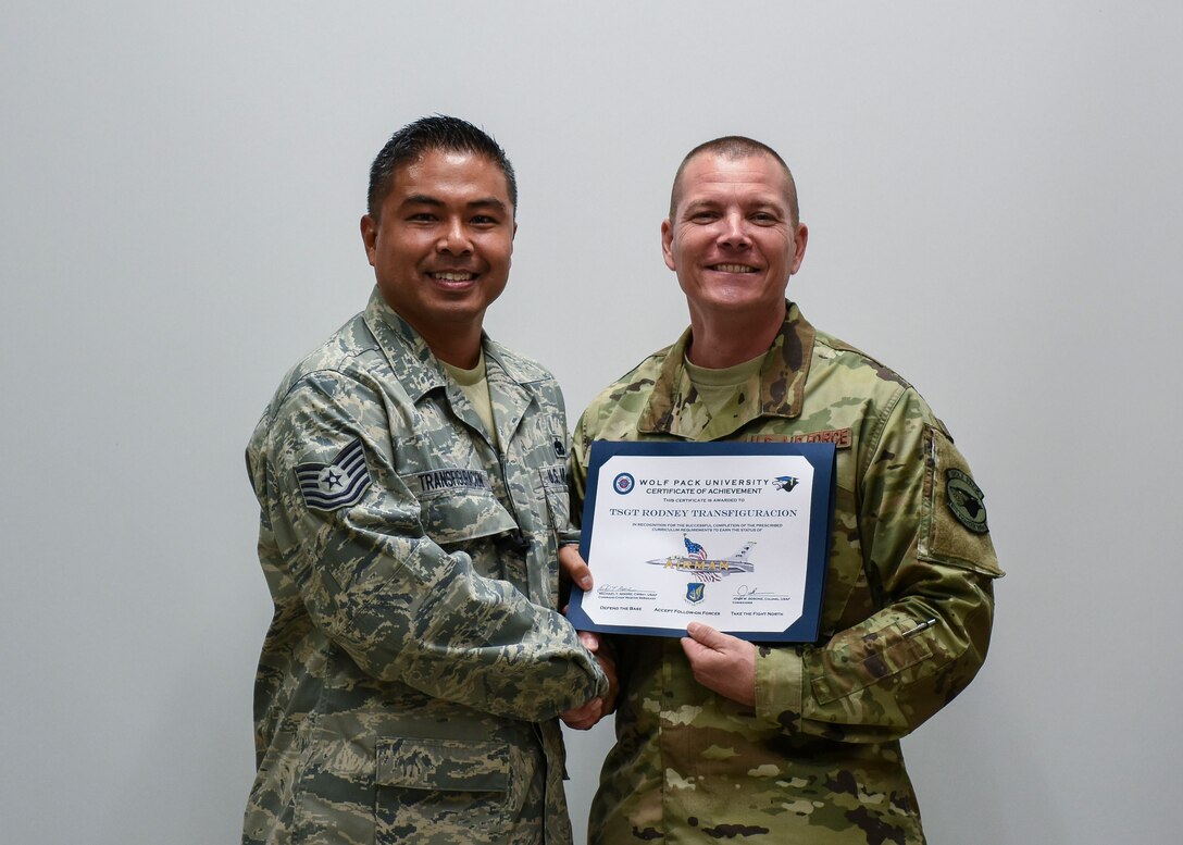 U.S. Air Force Tech. Sgt. Rodney Transfiguracion, 8th Maintenance Squadron unit deployment manager, receives a Wolf Pack University graduation certificate from Chief Master Sgt. Michael Moore, 8th Fighter Wing command chief, at Kunsan Air Base, Republic of Korea, Oct. 11, 2018. Wolf Pack University is a collegiate-mirrored system which includes a personalized curriculum, transcripts, advisors, electives and a diploma specific to being at Kunsan. (U.S. Air Force photo by Senior Airman Savannah L. Waters)