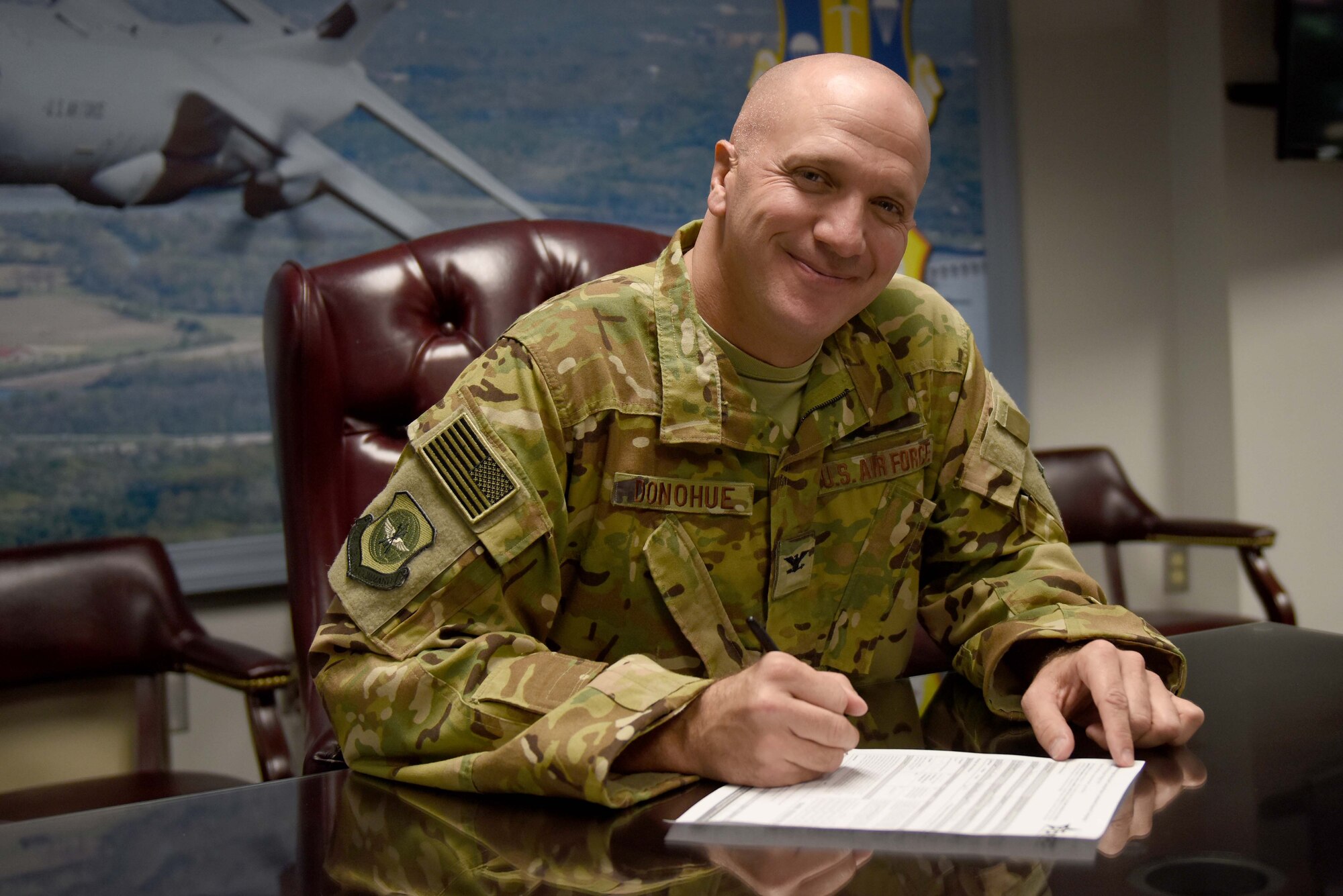 A man wearing the operational camouflage pattern uniform while writing on a piece of paper at a desk.