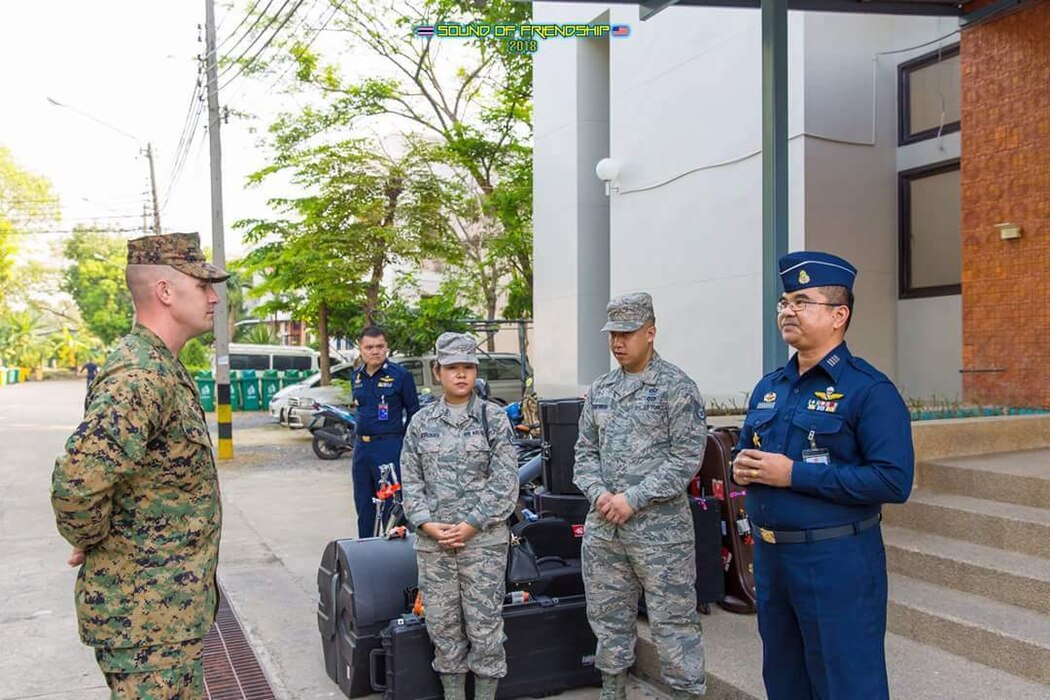 Five military members greeting in front of a building