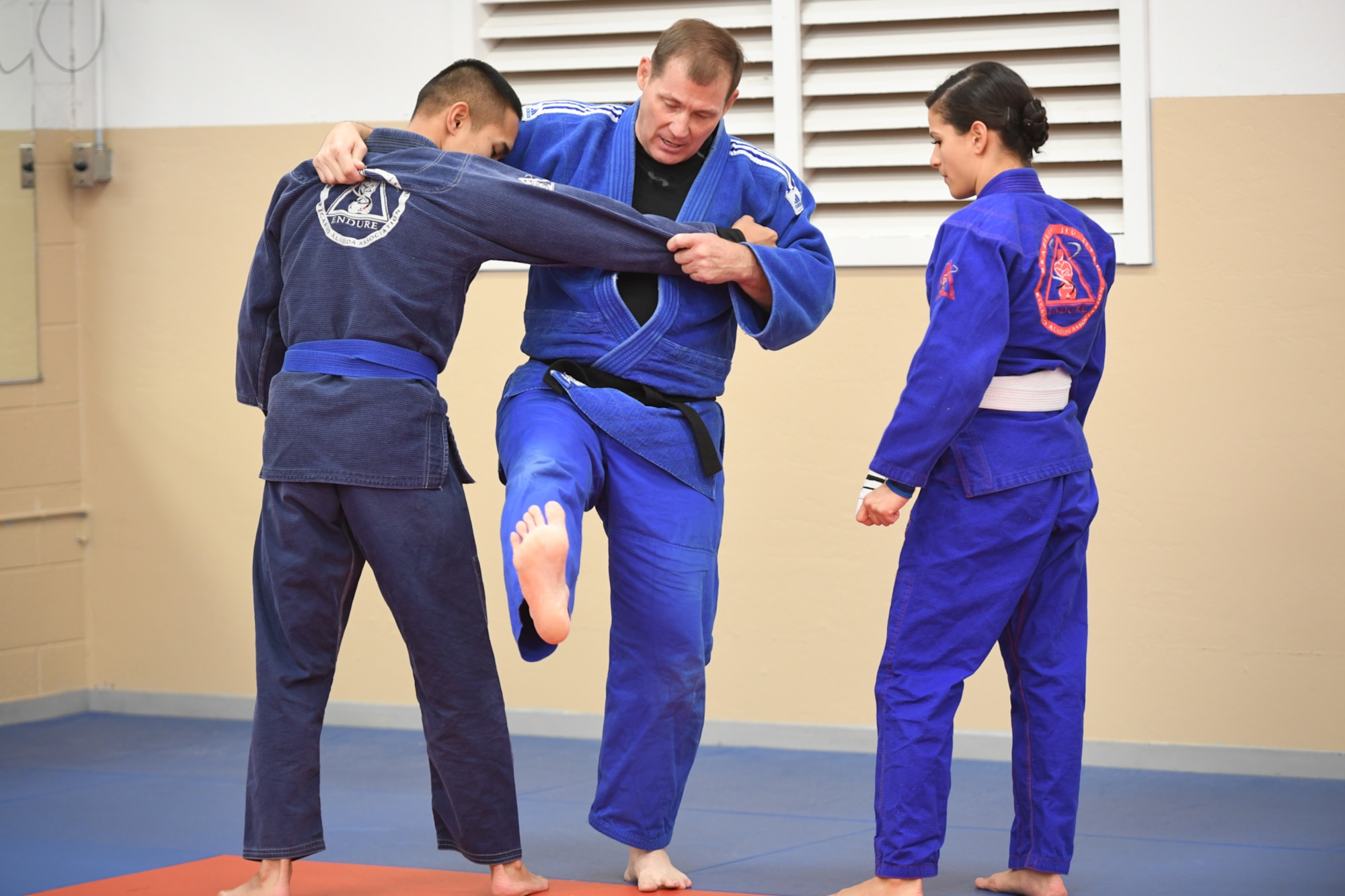 HIll Judo coach Don Chesmer helps Staff Sgt. Von Carios, 75th Medical Group, and Tech. Sgt. Tiffany Carios, 729th Air Control Squadron, with their foot-throwing technique during a free interactive training session at Hess Fitness Center on World Judo Day Oct. 30. (U.S. Air Force photo by Cynthia Griggs)
