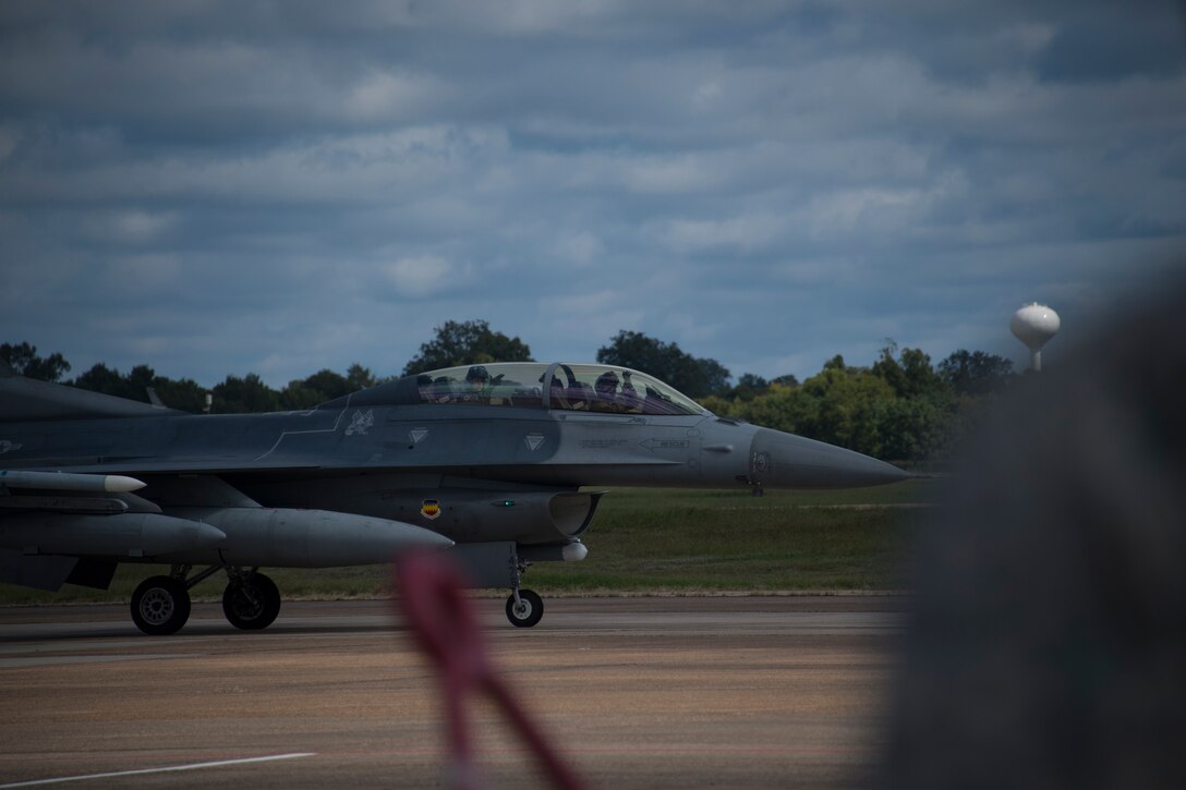 The pilot of an F-16 Fighting Falcon waves to an onlooker as he taxis down the runway at Barksdale Air Force Base, Louisiana, Oct. 10, 2018.   Several different types of jets took refuge at Barksdale AFB in preparation for Hurricane Michael. (U.S. Air Force photo by Master Sgt. Ted Daigle)