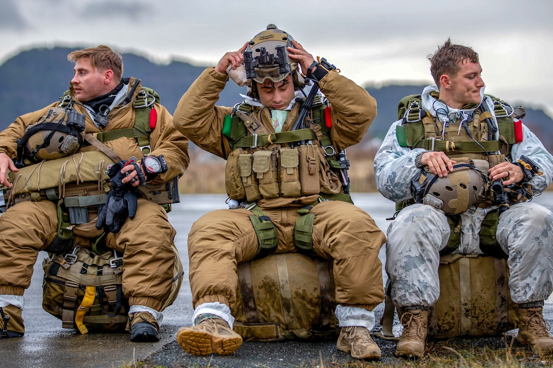 Three Marines sit on a dock waiting for an aircraft.
