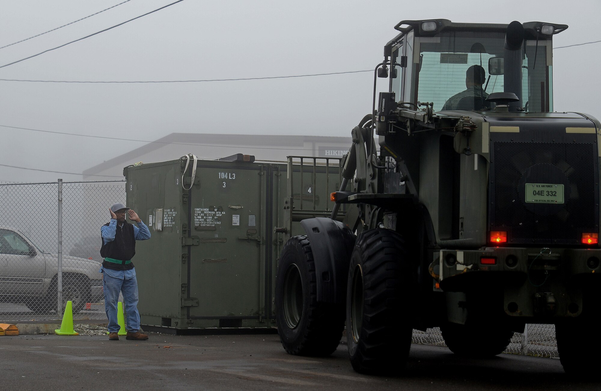 Ricky Underwood (left), 627th Logistics Readiness Squadron material expeditor, spots Staff Sgt. Christopher Sutton, 627th LRS vehicle equipment driver, while he lifts a container using a forklift Oct. 19, 2018 at Joint Base Lewis-McChord, Wash.