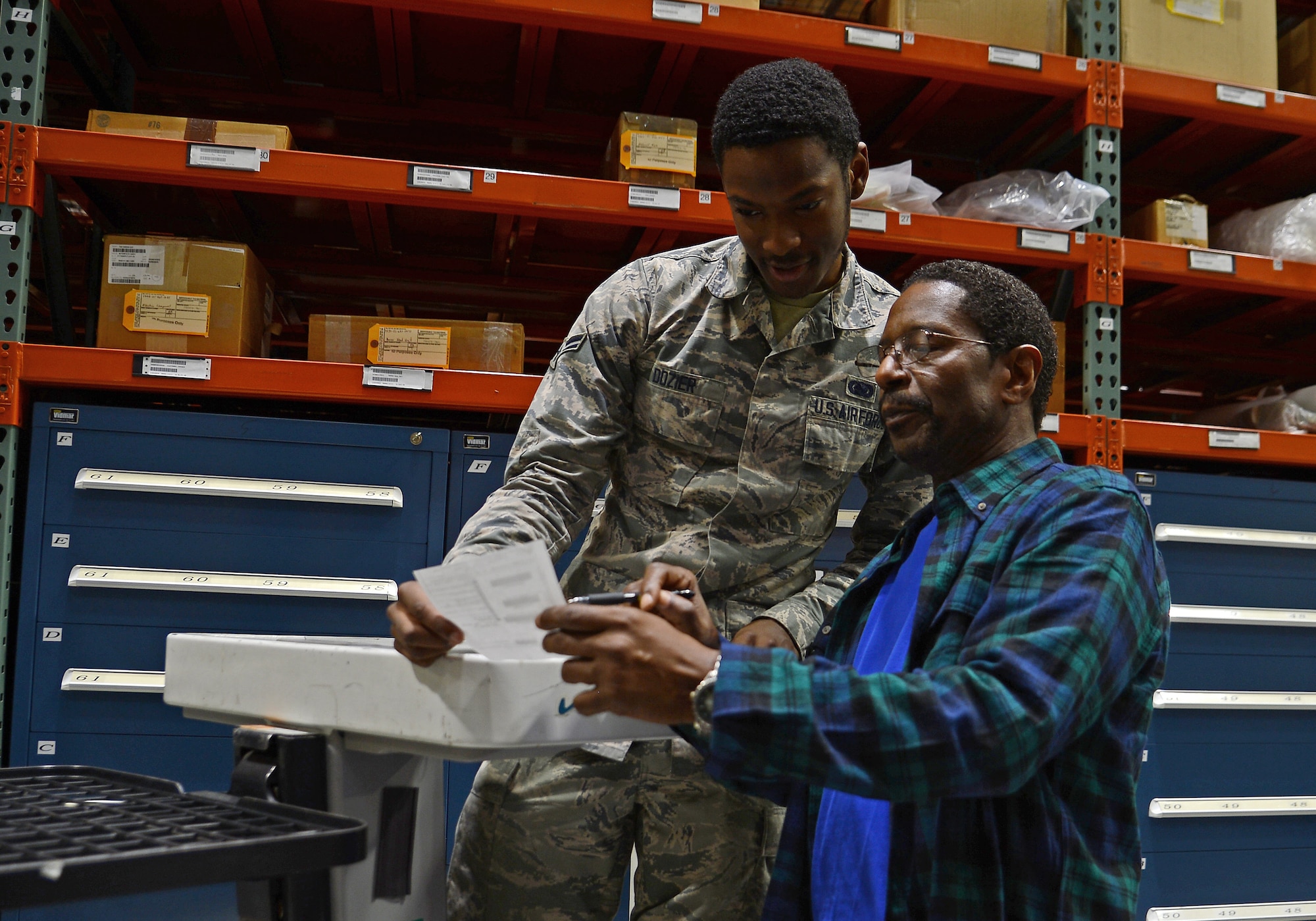 Airman 1st Class Joshua Dozier and Ronald Hines, 627th Logistics Readiness Squadron supply technicians, reviews a document before pulling an item off the warehouse shelf Oct. 19, 2018 at Joint Base Lewis-McChord, Wash.