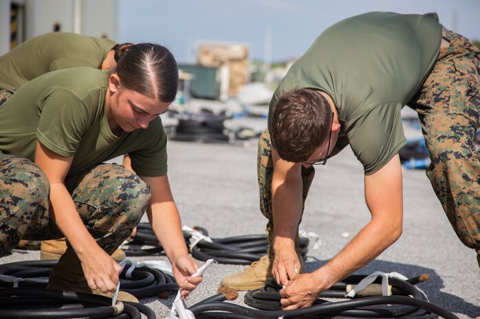 Pfc. Seaira Hack, left, and Pfc. Luis Mendoza, right, prepare wire feeder cables for inspection on Camp Kinser, Okinawa, Japan October 30, 2018. Wire feeder cables are used to support generators while Marines are in deployed environments. Hack and Mendoza are heavy equipment operators with Engineer Maintenance Company, Combat Logistics Regiment 35, 3rd Marine Logistics Group. Hack is a native of Graham, Texas. Mendoza is a native of San Clemente, California. (U.S. Marine Corps photo by Lance Cpl. Mark Fike)