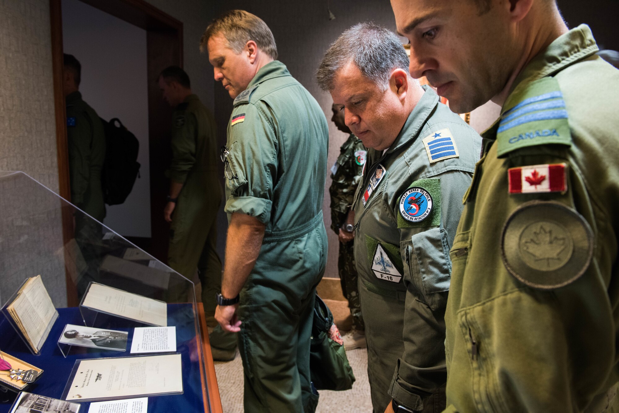 Foreign attaché members look at historical Pacific Air Forces (PACAF) photos and artifacts before entering the Kenney Conference Room at Headquarters PACAF during a tour of Joint Base Pearl Harbor-Hickam, Hawaii, Oct. 23, 2018.