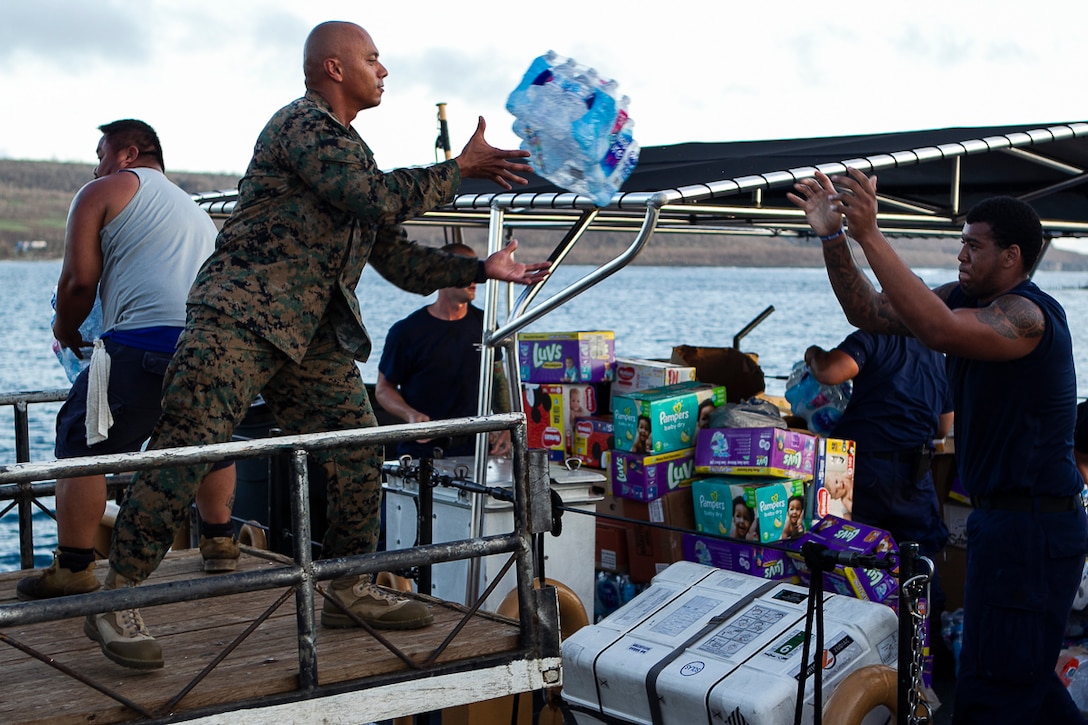 Gunnery Sgt. Angel Ignacio, the battalion gunnery sergeant with Combat Logistics Battalion 31, catches a package of bottled water from a coastguardsman aboard the U.S. Coast Guard Cutter Washington (WPB-1331) while delivering food and supplies to citizens of Tinian, Commonwealth of the Northern Mariana Islands during relief efforts in the wake of Super Typhoon Yutu, Oct. 29, 2018. Ignacio, a communications chief, is a native of Guam, CNMI, which was also affected by Yutu. The Marines arrived on Tinian in the wake of Super Typhoon Yutu as part of the U.S. Defense Support of Civil Authorities here. The Marines arrived at the request of CNMI officials and the U.S. Federal Emergency Management Agency to assist relief efforts in the wake of Yutu, the largest typhoon to ever hit a U.S. territory. The 31st MEU, the Marine Corps’ only continuously forward-deployed MEU, provides a flexible force ready to perform a wide-range of military operations across the Indo-Pacific region. (U.S. Marine Corps photo by Gunnery Sgt. T. T. Parish/Released)