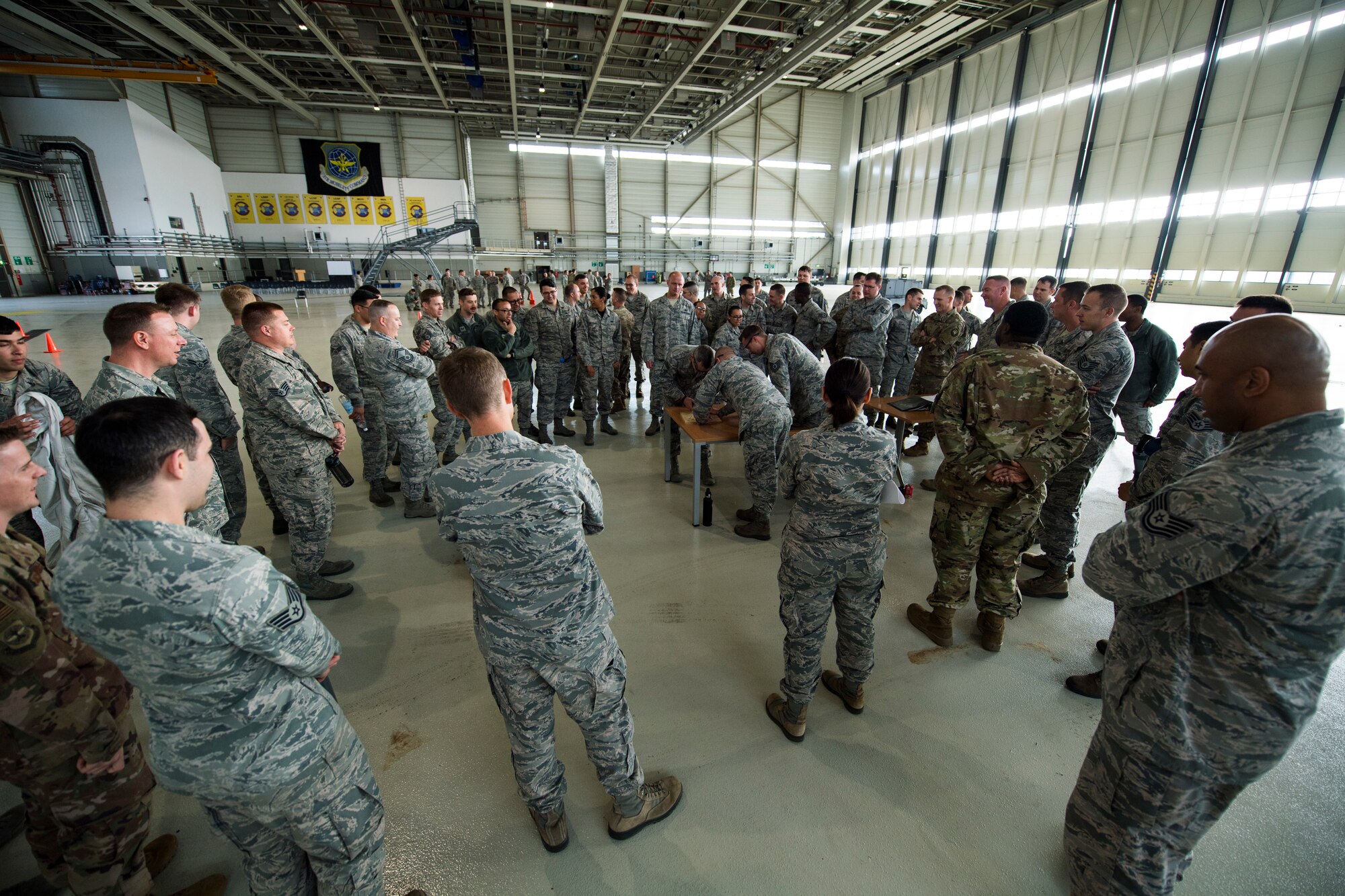 Members of the 721st Aircraft Maintenance Squadron and 721st Aerial Port Squadron watch as their leaders attempt to use safety wire to secure a bolt as part of the maintenance relay during the 721st Air Mobility Operations Group safety down day on Ramstein Air Base, Germany, Oct. 19, 2018. In addition to the relay, physical fitness, resilience and other wingman concepts were all included in the safety down day. (U.S. Air Force photo by Senior Airman Devin M. Rumbaugh)