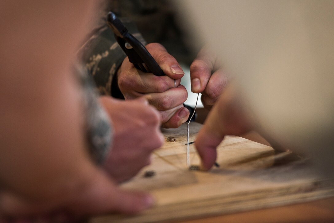 U.S. Airmen assigned to the 721st Aircraft Maintenance Squadron use safety wire to secure bolt as part of the maintenance relay during the 721st Air Mobility Operations Group safety down day on Ramstein Air Base, Germany, Oct. 19, 2018. In addition to the relay, physical fitness, resilience and other wingman concepts were all included in the safety down day. (U.S. Air Force photo by Senior Airman Devin M. Rumbaugh)