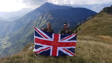 New York Army National Guard 1st Lt. Christian Larrabee, right, displays the United Kingdom colors at the conclusion of his Military Exchange Program training tour with British Army 2nd Lt. Max George, assigned to the Fifth Royal Regiment of Fusiliers following the Triglav Star 2018 multinational training exercise at the NATO Multinational Centre of Excellence for Mountain Warfare in the Julian Alps of Slovenia. Larrabee served as a platoon leader during company level training lanes in the mountain warfare exercise.