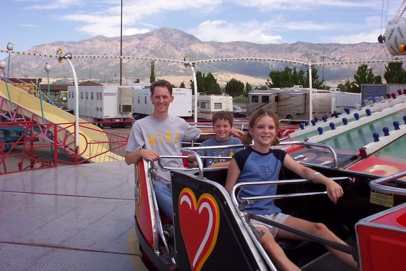 Three people enjoy an amusement park ride.