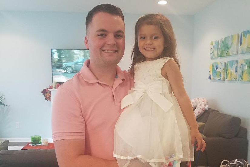 A father poses with his daughter in his arms.