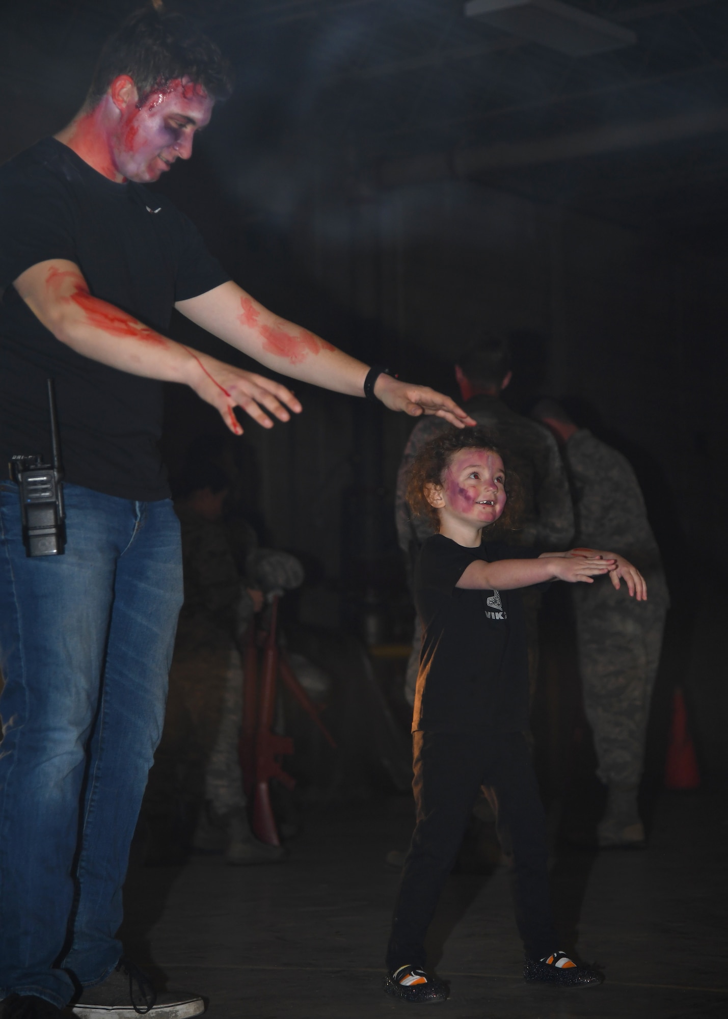 Kariana Henry, three years, shows off her zombie walk to an Operation Iron Zombie volunteer October 31, 2018, on Grand Forks Air Force Base. Iron Zombie was a Halloween-themed readiness exercise, with actors dressing up in spooky costumes to scare Airmen participating in the event. (U.S. Air Force photo by Airman 1st Class Elora J. Martinez)