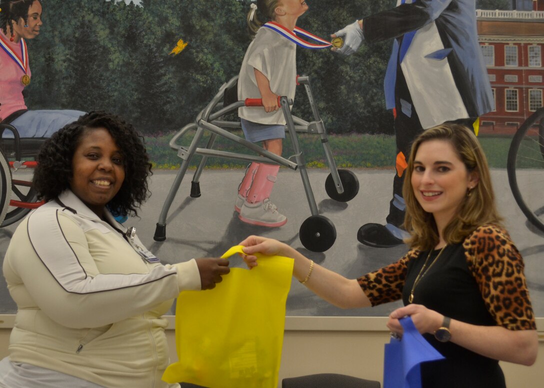 DLA Troop Support Industrial Hardware Success and Partnership in Reaching Excellence mentoring program co-lead and division chief Joanne Anello (right) hands activity bags to Shriners Hospital for Children – Philadelphia public relations employee Joy Young (left) at the hospital in Philadelphia Nov. 2, 2018.