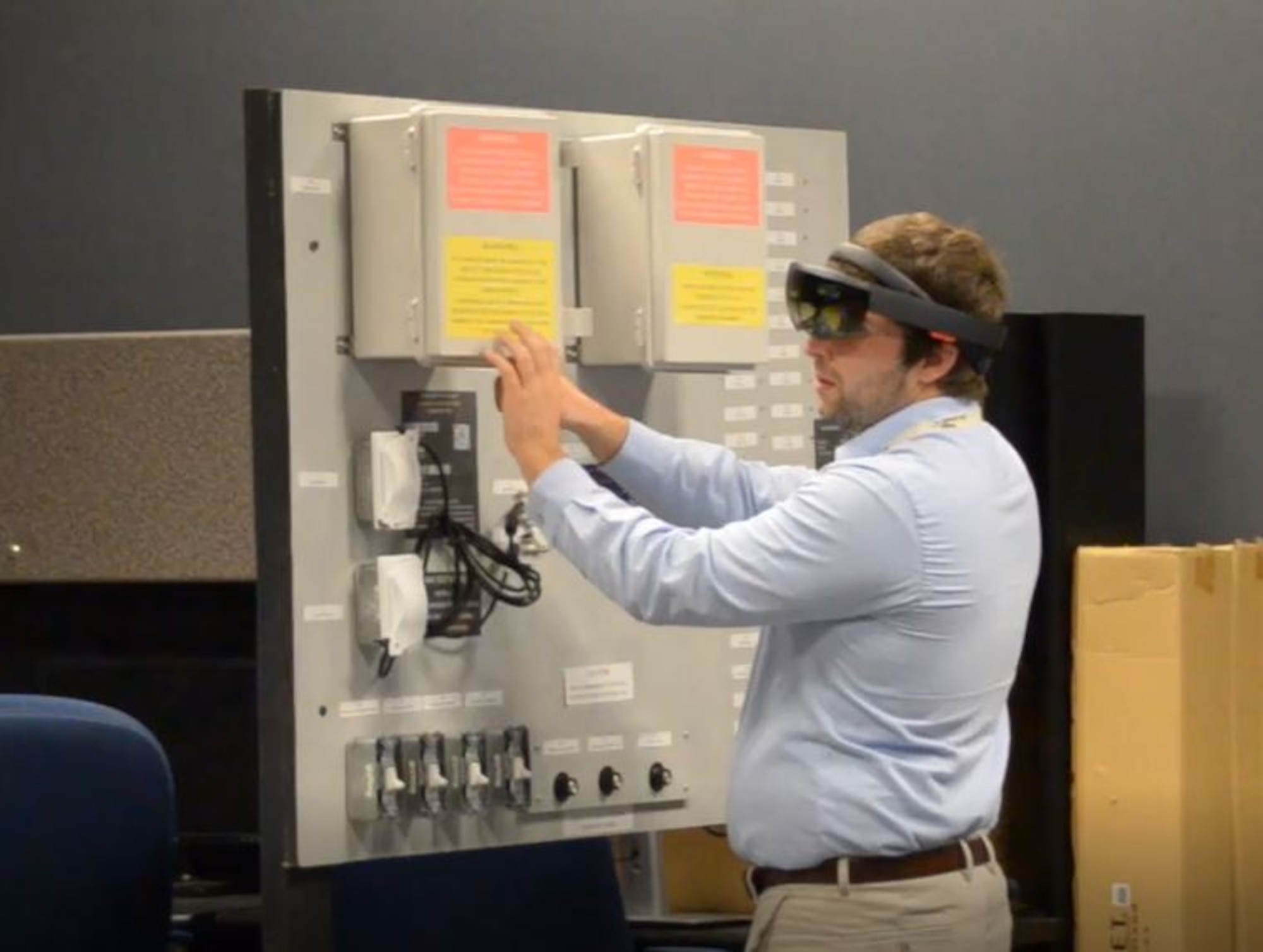 Team Collaborative Augmented Reality Maintenance Assistant (CARMA) member Bobby Samuel is guided through a repair action using CARMA. Samuel uses a demo board representative of support equipment a maintainer might interact with in the field to test the functionality of CARMA. (U.S. Navy photo)