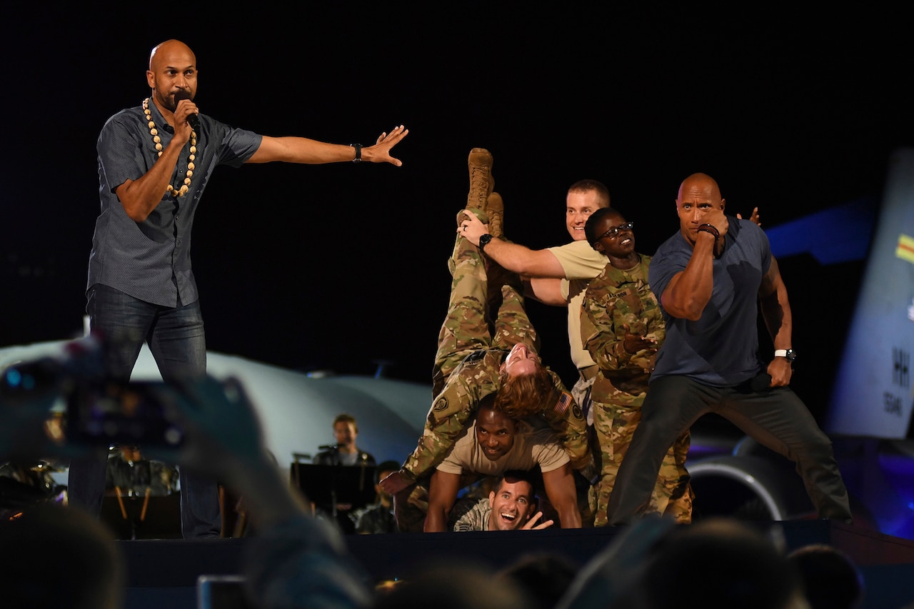 Actors pose on stage with service members