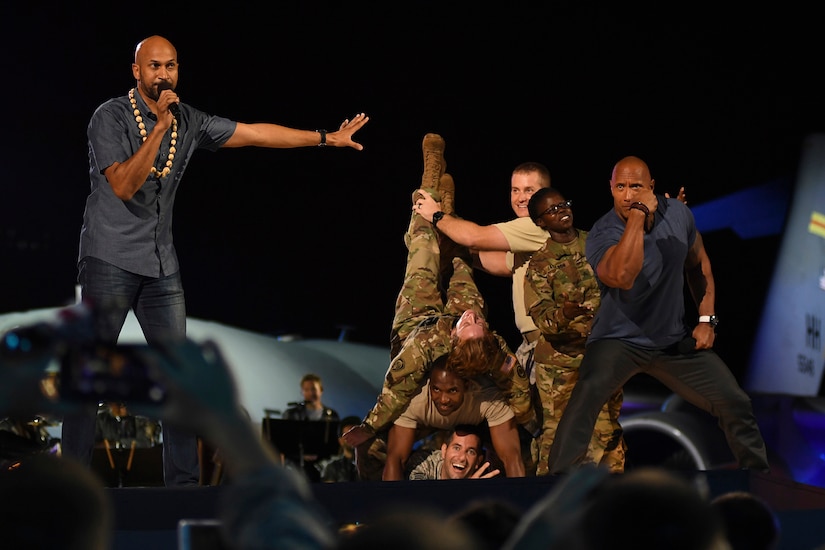 Actors pose on stage with service members