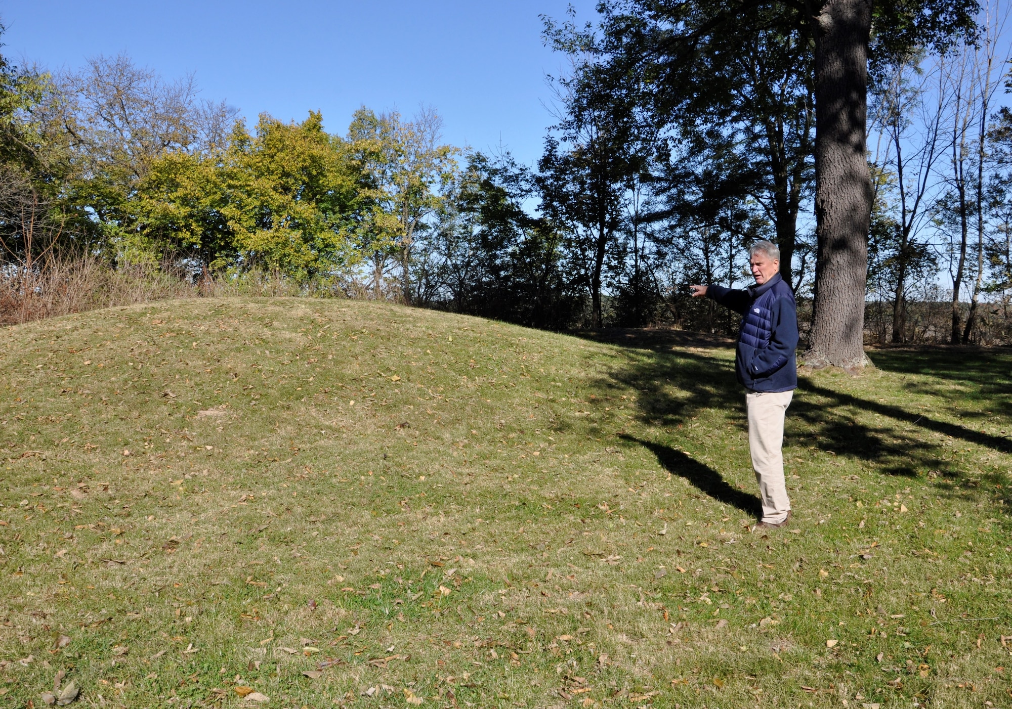 Erwin Roemer stands by the largest of the six Adena Mounds at the Wright Brothers Memorial off Kauffman Ave, Area B. The Wilbur and Orville Wright Commission and Carl Rust Parker of the Olmsted Brothers landscape architecture firm recognized the significance of the mounds and felt a plaque should be erected in their honor. (U.S. Air Force photo/W. Eugene Barnett)