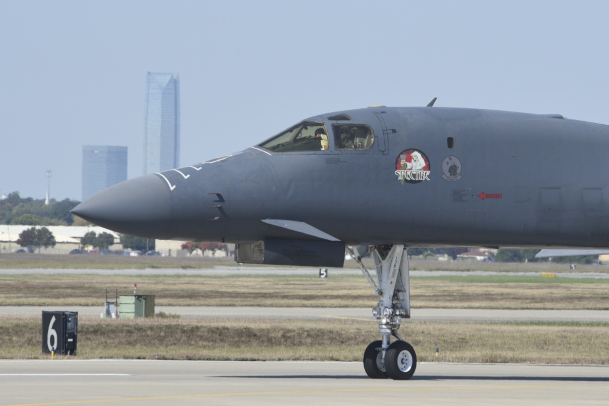 B-1B Lancer, 86-0109, 'Spectre' taxis at Tinker Air Force Base, Oklahoma, Oct. 26, 2018, with parts of the Oklahoma City skyline visible in the background. The jet was ferried from Midland International Air and Space Port to Tinker where it will undergo depot-level maintenance and upgrades with the Oklahoma City Air Logistics Complex today. During a routine training flight May 1, the Dyess AFB based B-1B had an in-flight emergency resulting in an attempted ejection. The first crewmembers’ seat failed to deploy and the aircraft commander halted the ejection sequence and heroically saved the aircraft and crew by landing at Midland International Air & Space Port.