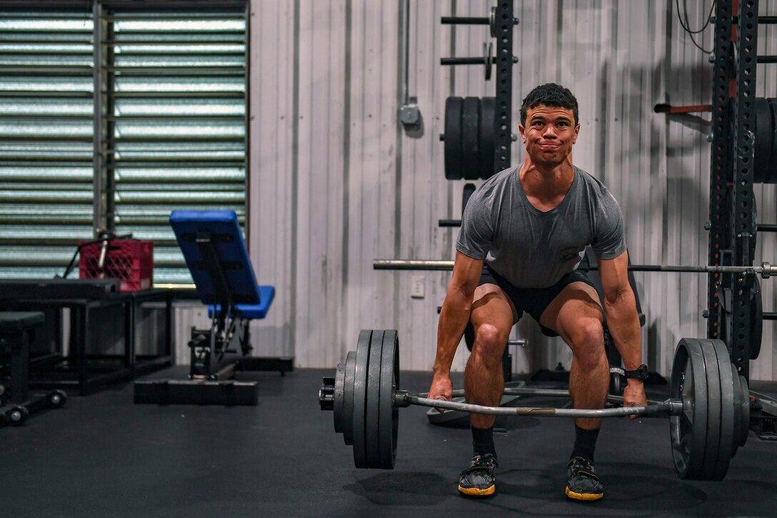 An airmen deadlifts a barbell.