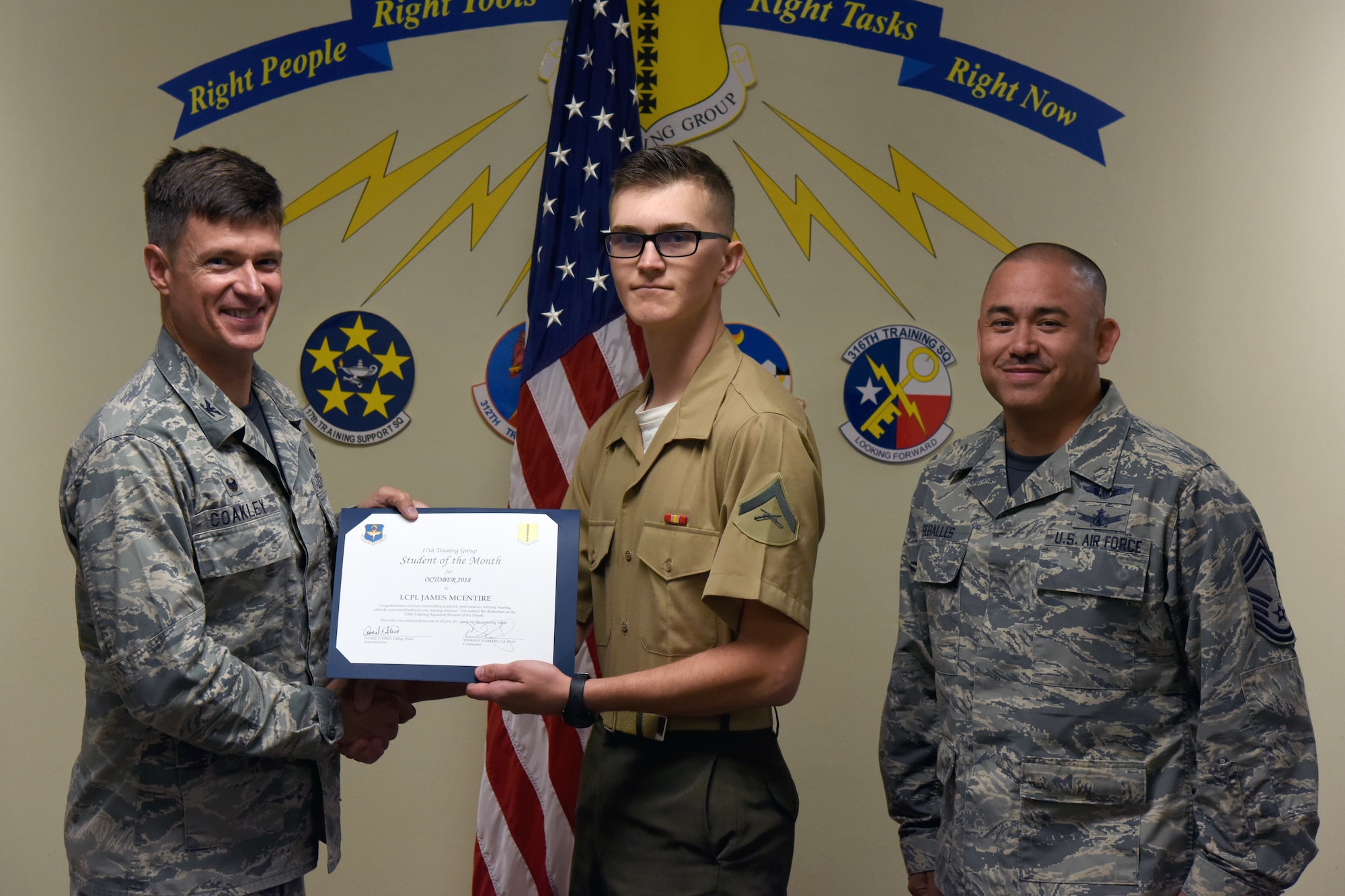 U.S. Air Force Col. Thomas Coakley, 17th Training Group commander, presents the 316th Training Squadron Student of the Month award to Lance Cpl. James Mcentire, 316th TRS student, at Brandenburg Hall on Goodfellow Air Force Base, Texas, Nov. 2, 2018. The 316th TRS’s mission is to conduct U.S. Air Force, U.S. Army, U.S. Marine Corps, U.S. Navy and U.S. Coast Guard cryptologic, human intelligence and military training. (U.S. Air Force photo by Airman 1st Class Zachary Chapman/Released)