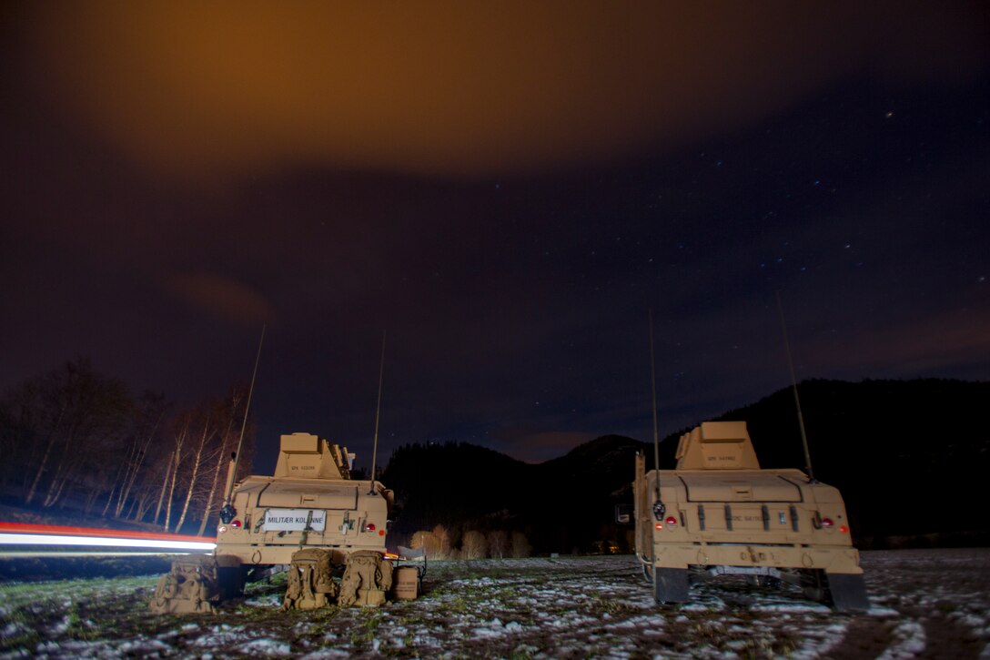 Marines congregate around Humvees and survey their surroundings as night falls.
