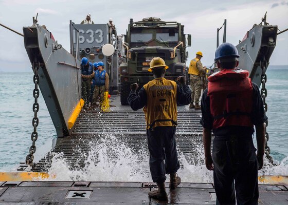 OKINAWA, Japan (Oct. 29, 2018) Boatswain’s Mate 3rd Class Nayyaamunhotep Stubbs signals the Landing Craft, Utility (LCU) 1633 to approach the well deck of the amphibious dock landing ship USS Ashland (LSD 48) to receive equipment in preparation to conduct Defense Support to Civil Authorities (DSCA) efforts. Sailors and Marines from Ashland, part of the Wasp Amphibious Ready Group and 31st Marine Expeditionary Unit team, are preparing to provide Department of Defense support to the Commonwealth of the Northern Mariana Islands’ civil and local officials as part of the FEMA-supported Typhoon Yutu recovery efforts.