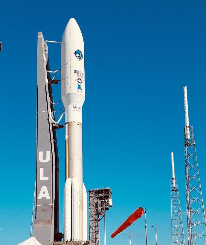 Large white rocket stands ready for launch against a deep blue sky.