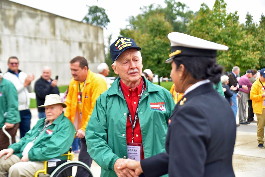 A cadet shakes the hand of a Vietnam veteran.