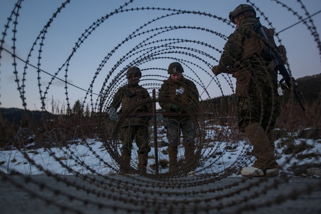U.S. Marine Corps, Sgt. Michael Wilson, center, with Bridge Company, 8th Engineer Support Battalion, 2nd Marine Logistics Group-Forward, set up concertina wire during security set up before a bridging operation during Exercise Trident Juncture 18 near Voll, Norway, Oct. 29, 2018. The bridge construction enables ground units to complete a gap crossing during the exercise, which is one of the general engineering tasks 2nd MLG provides to the Marine Air-Ground Task Force. Trident Juncture 18 enhances the U.S. and NATO Allies’ and partners’ abilities to work together collectively to conduct military operations under challenging conditions. (U.S. Marine Corps photo by Lance Cpl. Scott R. Jenkins)