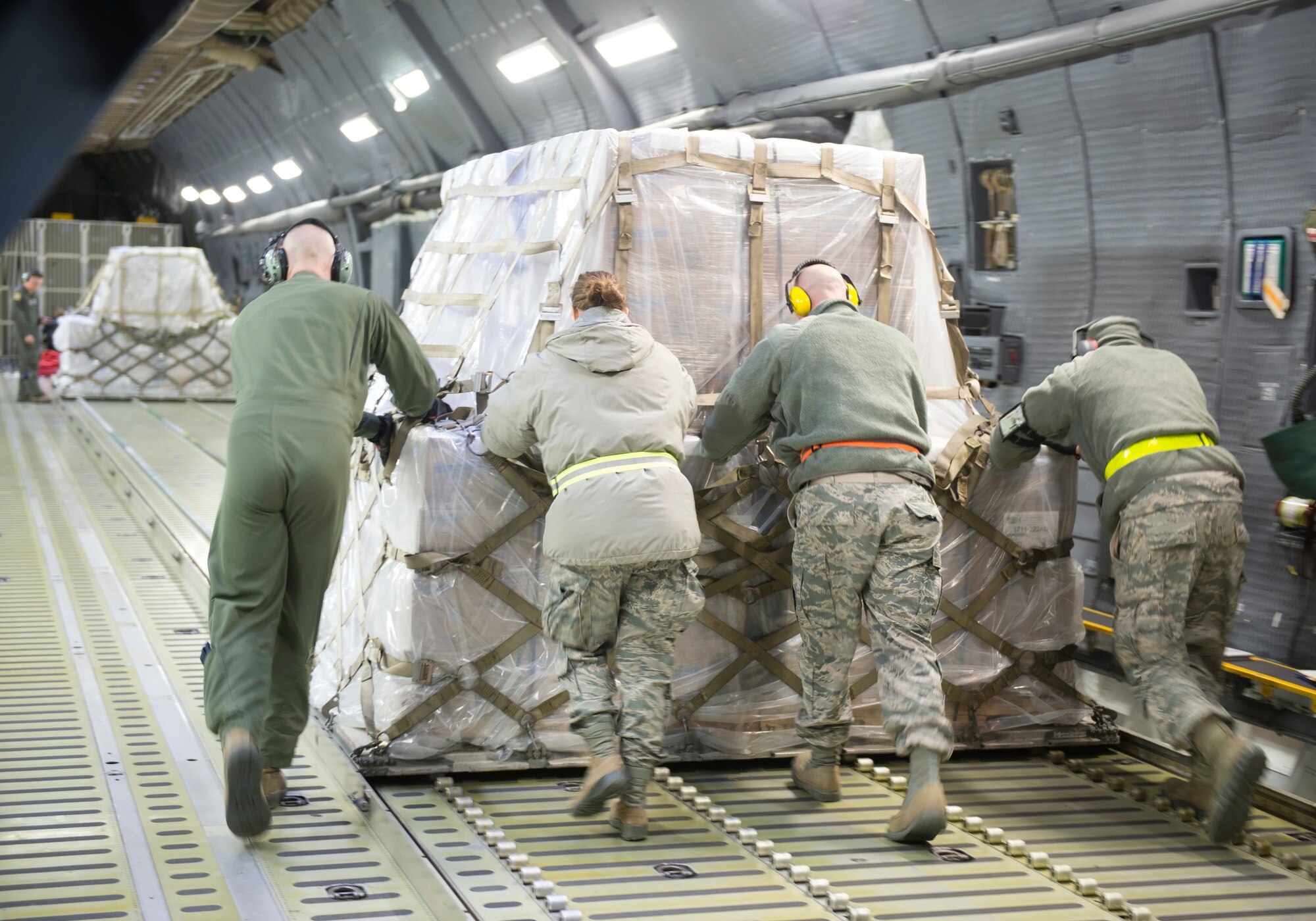Airmen from the 49th Aerial Port Squadron and the 337th Airlift Squadron push cargo into place during a Denton humanitarian aid mission Nov. 2, 2018 at Grissom Air Reserve Base, Indiana. The 84,700 pounds of cargo contained nearly 500,000 meals that are headed for Afghanistan.(U.S. Air Force photo/Tech. Sgt. Jami K. Lancette)