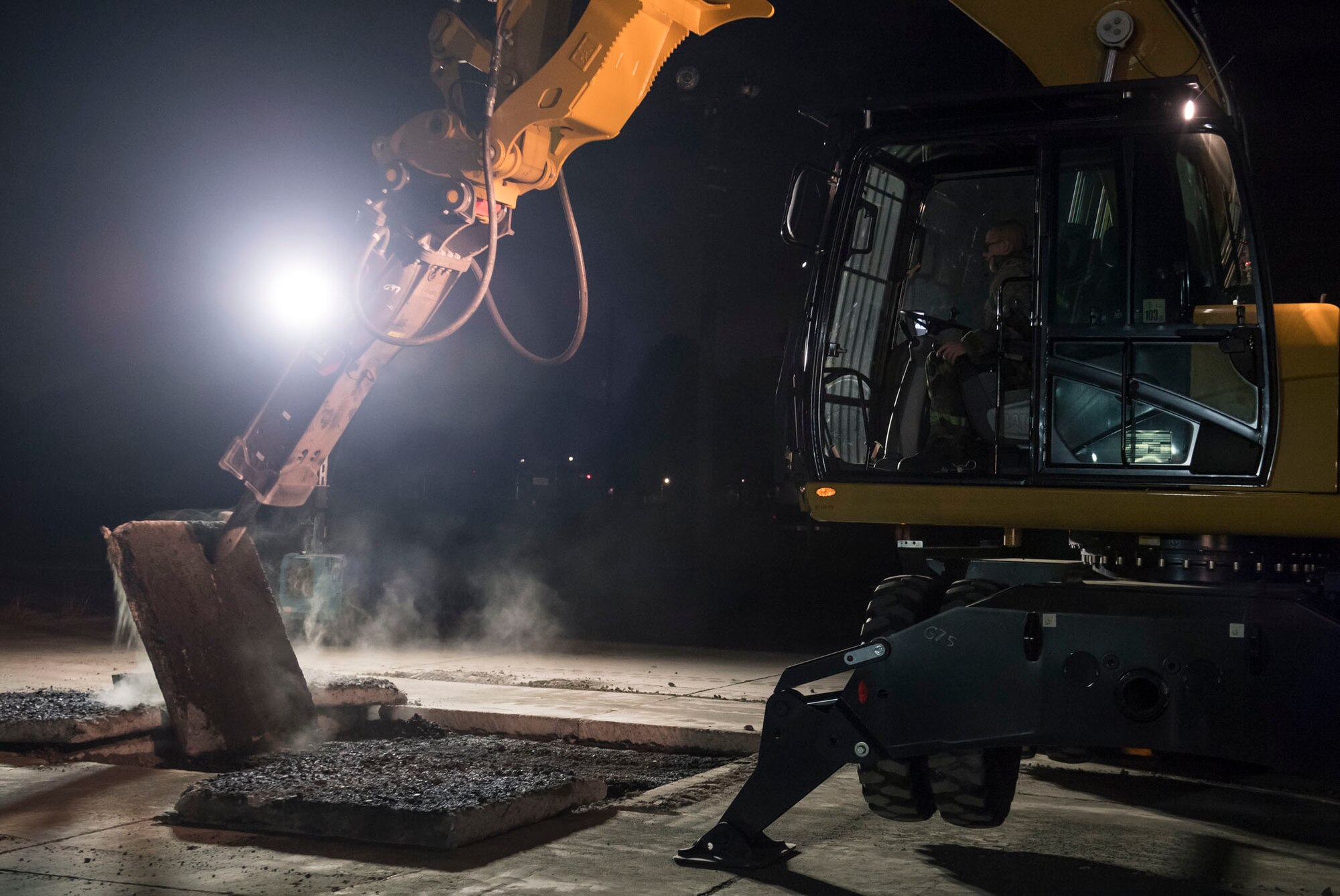 An Airman with the 374th Civil Engineer Squadron runs a wheel excavator to move a piece concrete for Rapid Airfield Damage Repair (RADR) during Exercise Beverly Morning 18-04, at Yokota Air Base, Japan