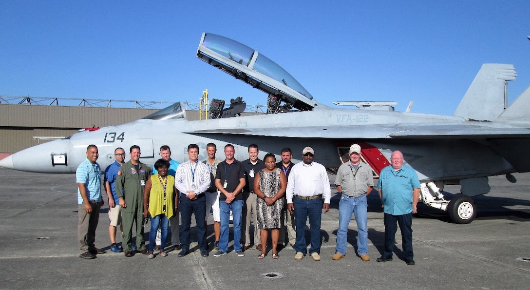 Group photo of males and females standing in front of a jet